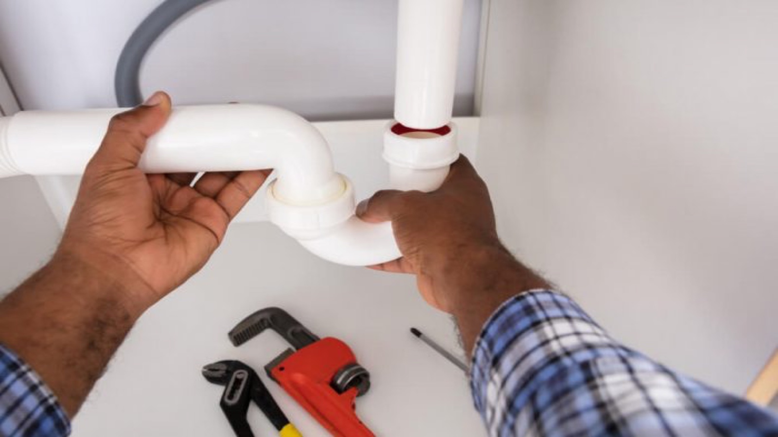 Plumber fitting a new P-trap beneath a sink